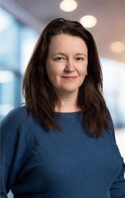 Logical BI founder Pauline wearing a dark blue jumper, her long brown hair is loose and she is smiling at the camera