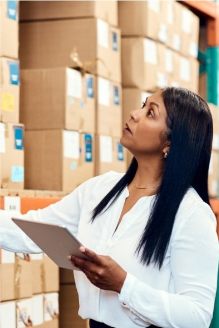 Image of a worker checking stock in a warehouse full of products