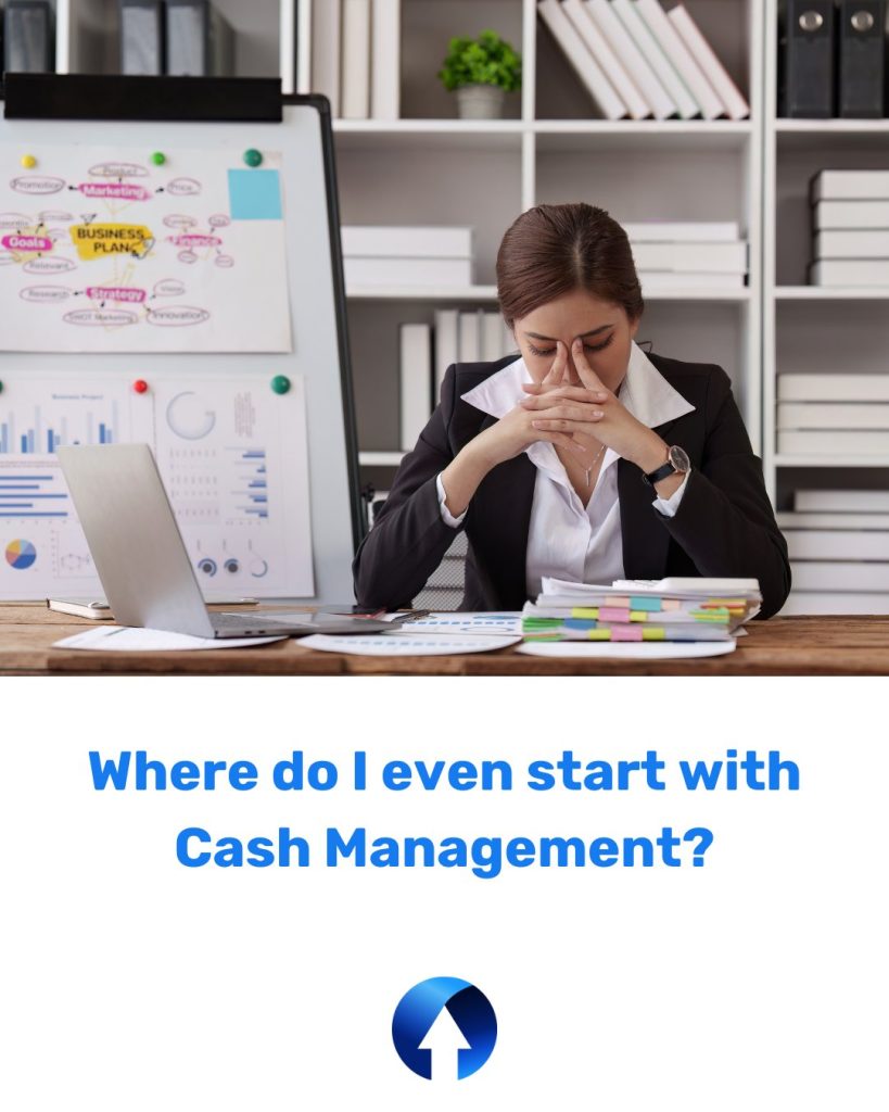 A lady sits at her desk with her face in her hands, she has paperwork on her desk and a whiteboard of post-it notes