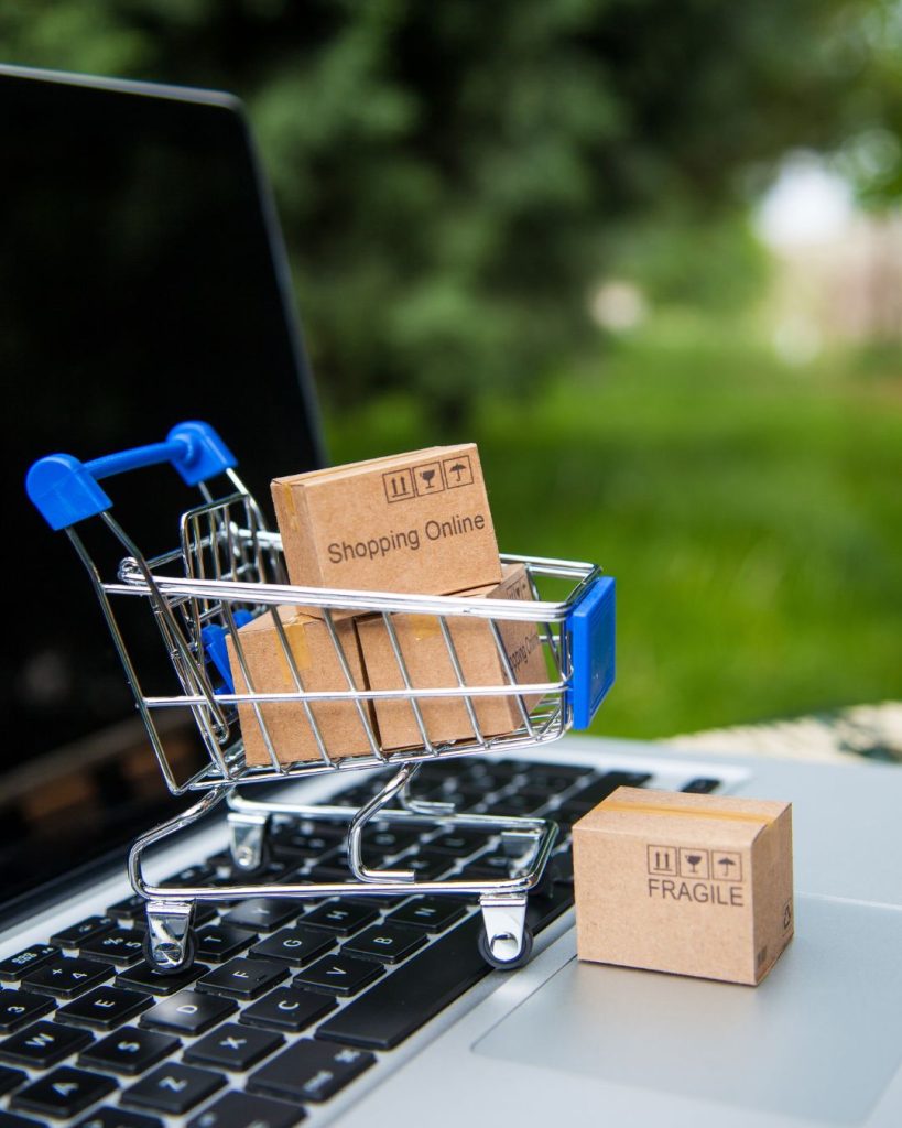 A small trolly with tiny brown boxes is placed on top of an open laptop to demonstrate Amazon FBA Accounting