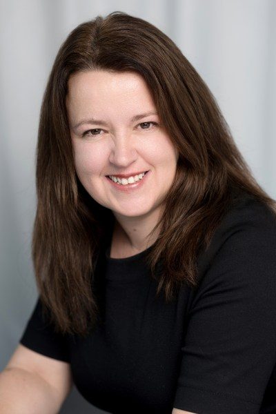 CFO Support membership founder Pauline Healey headshot. She has long brown hair and smiles at the camera wearing a black t-shirt.