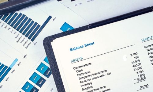 Lots of financial documents and graphs on a desk with a calculator