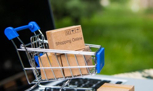 A small trolly with tiny brown boxes is placed on top of an open laptop to demonstrate Amazon FBA Accounting
